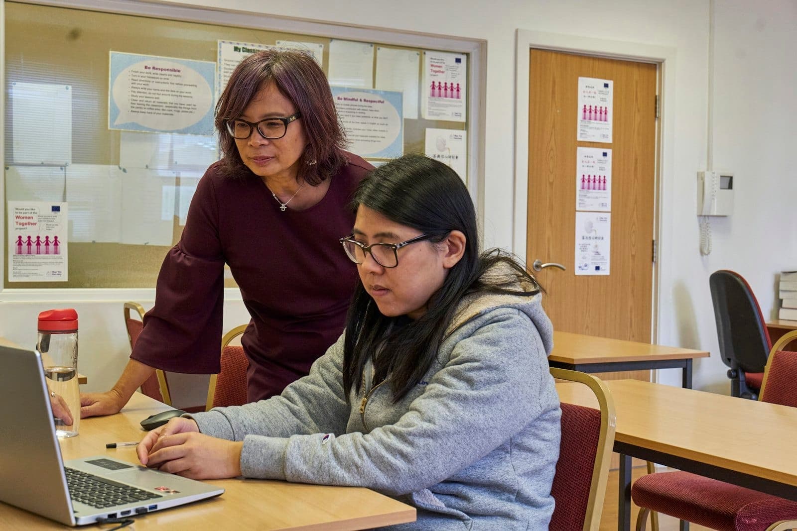 A teacher working one-to-one with a student at a laptop