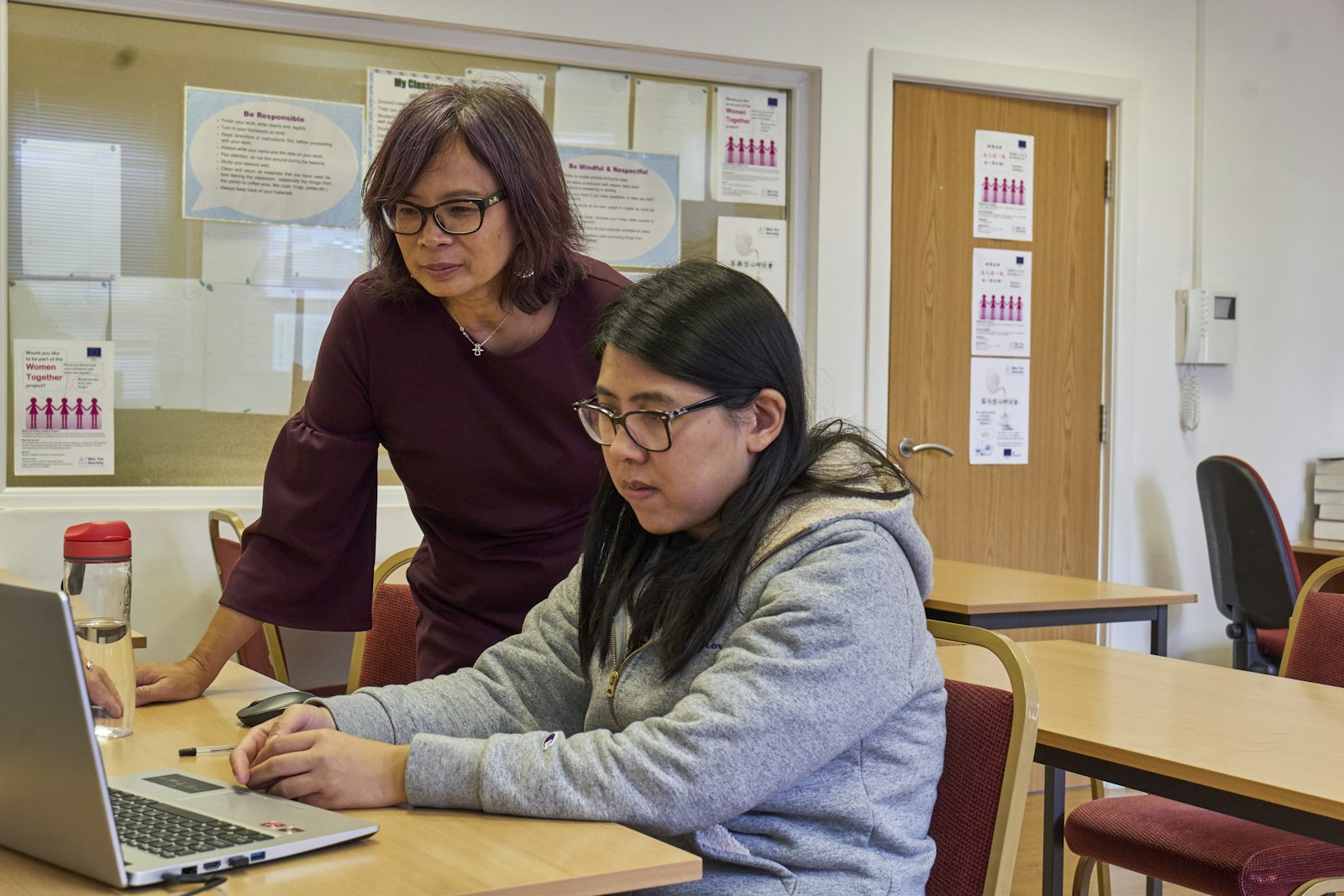 A teacher working one-to-one with a student at a laptop