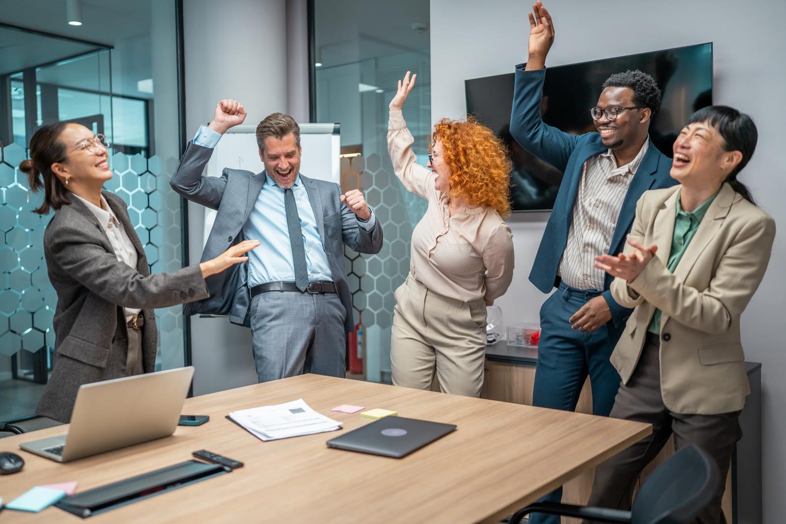 A diverse team celebrating together in a modern meeting room